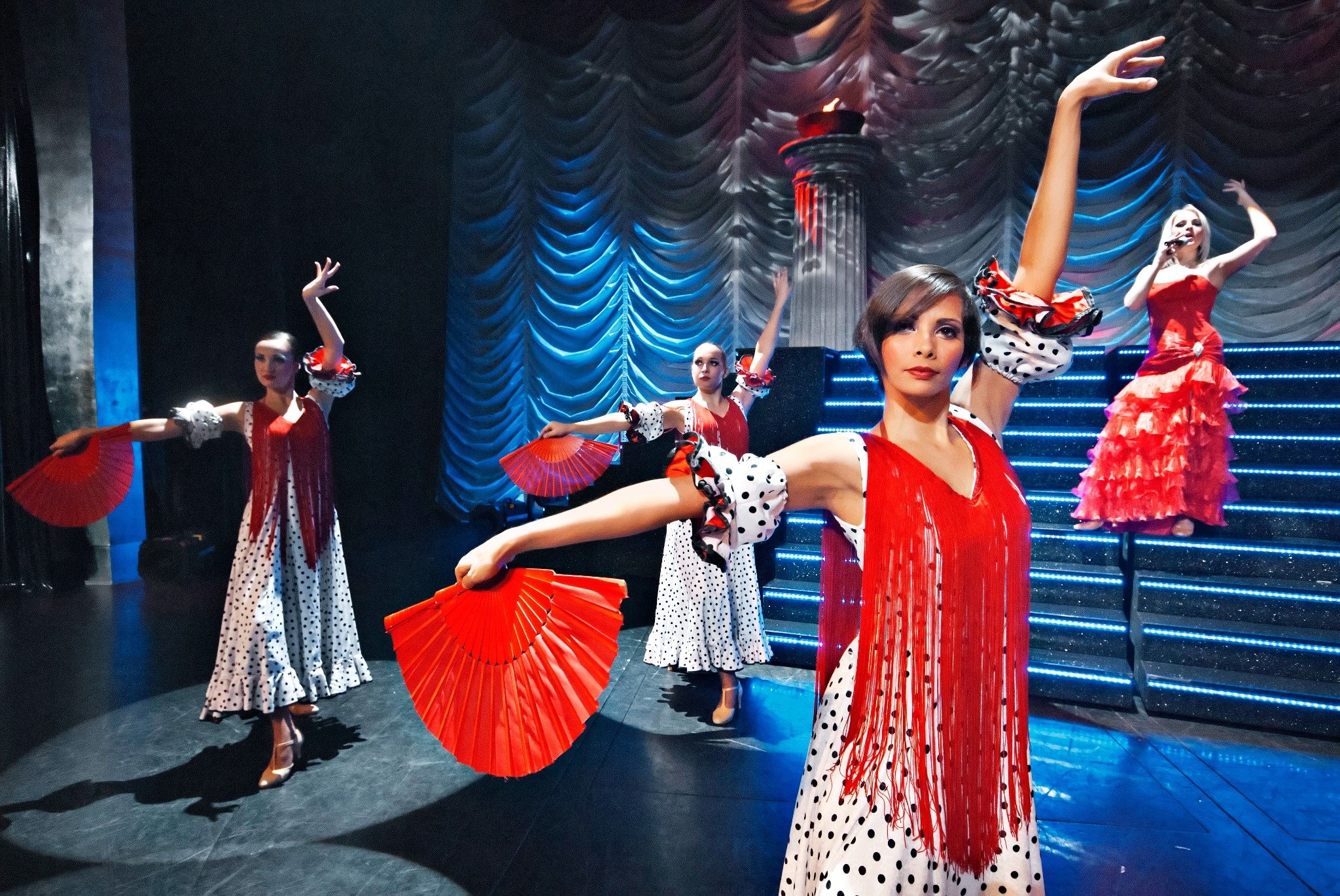 Dançarinas em trajes flamencos, segurando leques vermelhos e performando no palco, Dança Flamenca | MSC Cruzeiros 