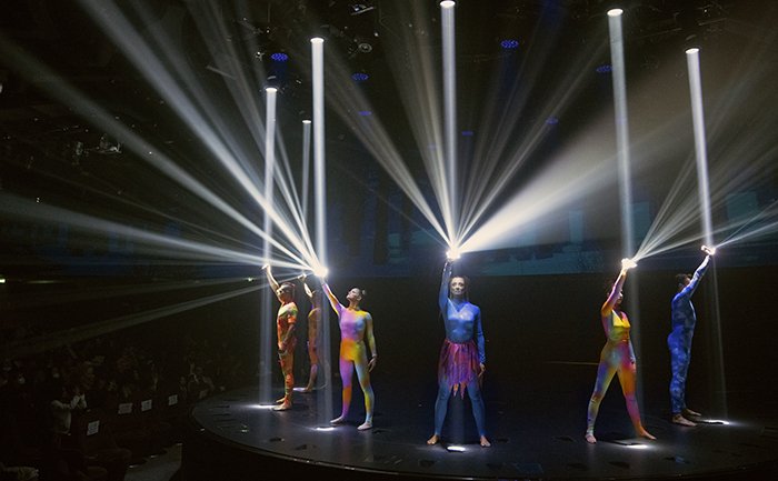 Performers in colorful costumes under dramatic lights during an onboard show | MSC Cruises Performers in colorful costumes under dramatic lights during an onboard show | MSC Cruises