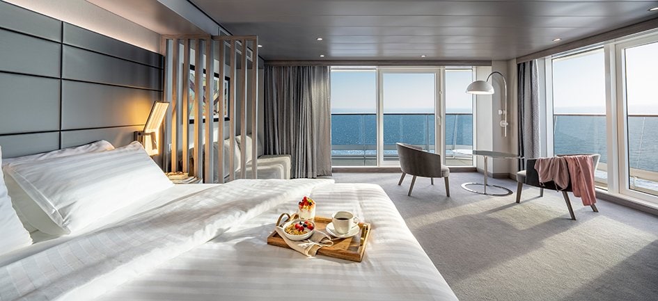 Luxury cruise suite with ocean view, private balcony, and breakfast tray on bed | MSC Cruises Luxury cruise suite with ocean view, private balcony, and breakfast tray on bed | MSC Cruises