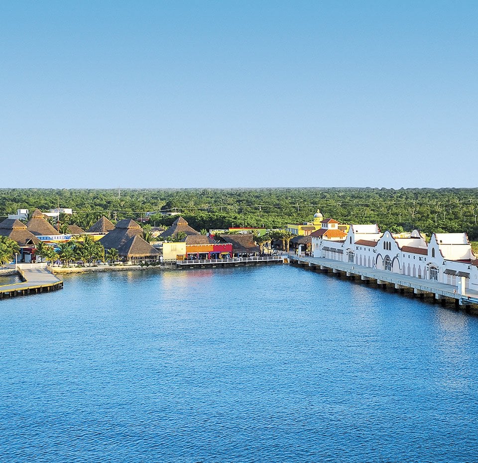 A vibrant port in Cozumel with colorful buildings and lush greenery | MSC Cruises A vibrant port in Cozumel with colorful buildings and lush greenery | MSC Cruises