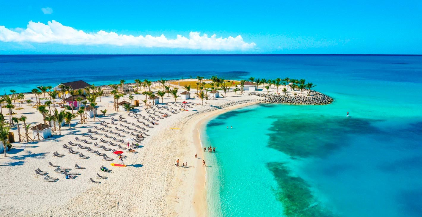 A pristine white sand beach with turquoise waters and palm trees on a private island | MSC Cruises