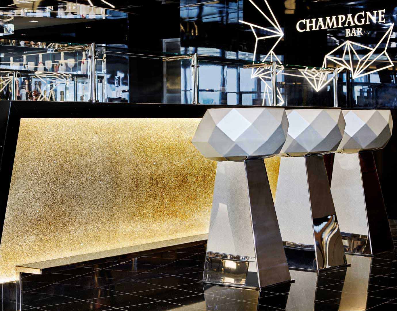 Luxurious champagne bar with geometric stools and golden accents onboard | MSC Cruises Luxurious champagne bar with geometric stools and golden accents onboard | MSC Cruises