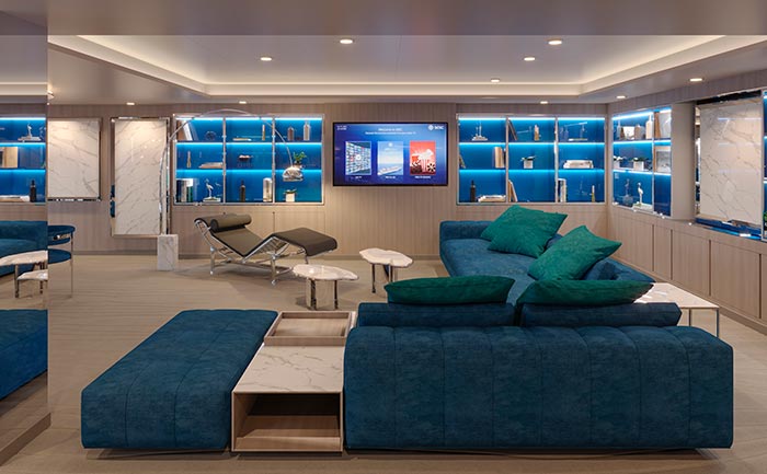 Luxurious lounge with modern blue seating and illuminated shelves onboard | MSC Cruises Luxurious lounge with modern blue seating and illuminated shelves onboard | MSC Cruises
